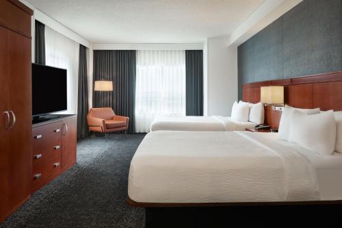 a hotel room with two beds and a flat screen tv at Courtyard by Marriott Calgary Airport in Calgary
