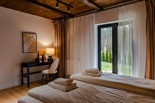 sypialnia z 2 łóżkami, biurkiem i oknem w obiekcie Przystań Roztocze, nowoczesny dom z sauną i jacuzzi w mieście Susiec