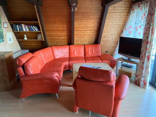 a living room with orange furniture and a flat screen tv at Ferienpark Fedderwardersiel in Fedderwarderdeich