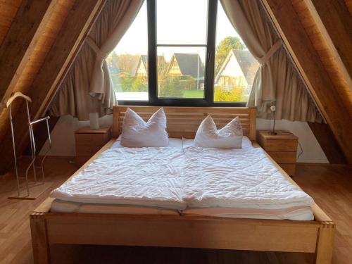 a bed with white sheets and pillows in a room with windows at Ferienpark Fedderwardersiel in Fedderwarderdeich