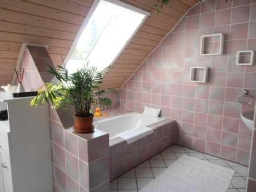 タープにあるPrivatzimmer Frankのピンクのタイル張りのバスルーム(バスタブ付)、窓が備わります。