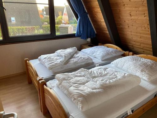 two twin beds in a room with two windows at Ferienpark Fedderwardersiel in Fedderwarderdeich