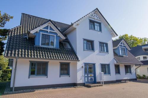 a white house with blue windows and a roof at Ferienwohnung Meeresrauschen in Zingst