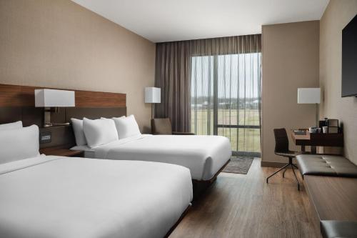 リッジランドにあるAC Hotel by Marriott Jackson Ridgelandのベッド2台とデスクが備わるホテルルームです。