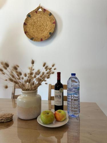 a bottle of wine and two apples on a table at Villa Saint George - Stone Costa in Kathikas