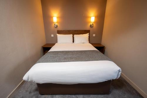 a large bed in a small room with two lamps at Wellington Hotel by Greene King Inns in Aberdeen