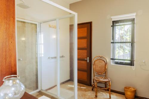 a glass shower door in a bathroom with a chair at Le Morne Vista in Le Morne