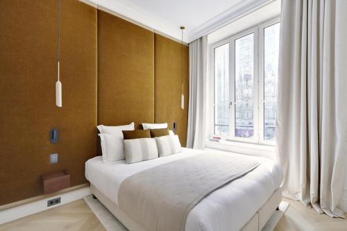 una camera da letto con un letto grande e una grande finestra di TheLander - Serviced Apartments in Louvre - Rivoli a Parigi