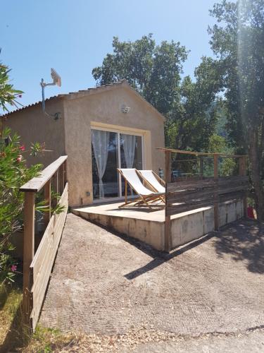 une maison avec une terrasse couverte et une clôture en bois dans l'établissement Maison 38m2 15min de Corte 30min de Bastia, à Bigorno