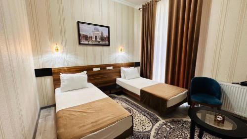une chambre d'hôtel avec deux lits et une chaise dans l'établissement Garden Plaza Bukhara, à Boukhara