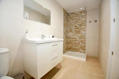 y baño blanco con lavabo y ducha. en Spacious apartment with AC in San Vicente en San Vicente del Raspeig