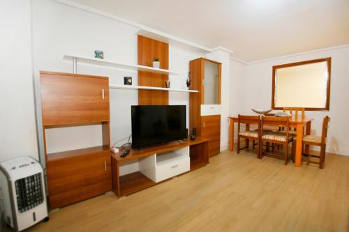 sala de estar con TV de pantalla plana y mesa en Spacious apartment with AC in San Vicente en San Vicente del Raspeig