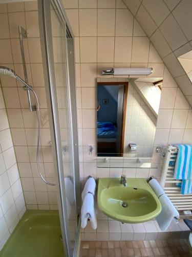 La salle de bains est pourvue d'un lavabo vert et d'une douche. dans l'établissement Oberdeck, à Norderney