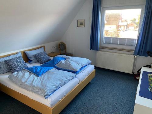 een slaapkamer met een bed met blauwe lakens en een raam bij Oberdeck in Norderney