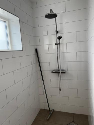 um chuveiro com uma varinha numa casa de banho em azulejos brancos em Hallands Equestrian Center em Laholm