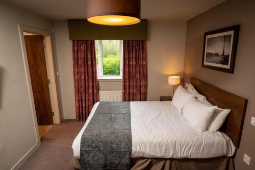 a bedroom with a bed and a window at Wellington Hotel by Greene King Inns in Aberdeen
