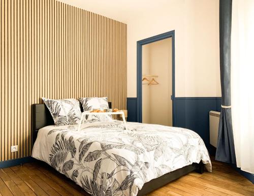 een slaapkamer met een bed met een gestreepte muur bij L’Estaminet 