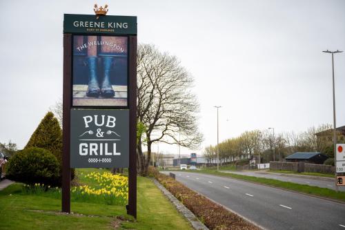 a sign for a pub and grill on the side of a road at Wellington Hotel by Greene King Inns in Aberdeen
