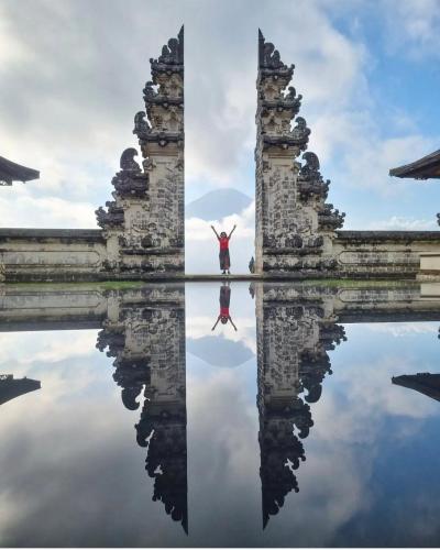 a woman standing on the water between two ruins at Batur cottage in Kubupenlokan
