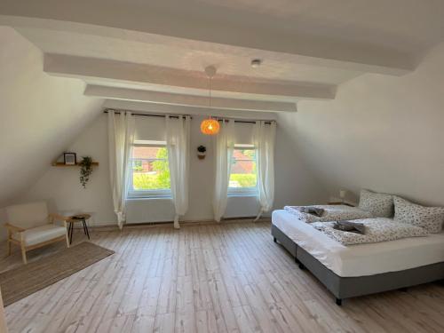 sypialnia z łóżkiem i kanapą oraz 2 oknami w obiekcie Villa Pewsum w mieście Krummhörn