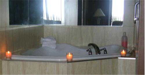 a bath tub with two candles in front of a mirror at Talbot Trail Inn & Suites in Leamington