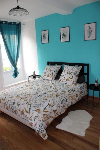 Ce lit se trouve dans une chambre aux murs bleus. dans l'établissement Koh'm à la maison, à Isigny-sur-Mer