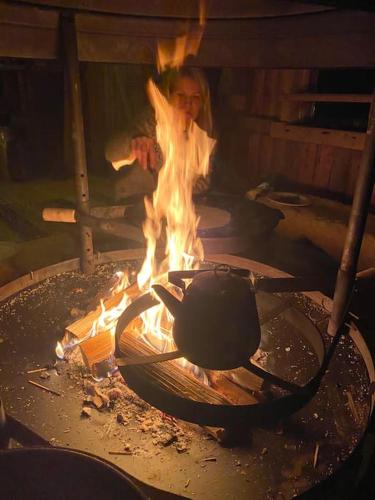 a person is standing next to a grill with fire at Laattajan Pirtti vuokramökki 1-5 henkilölle in Hyrynsalmi
