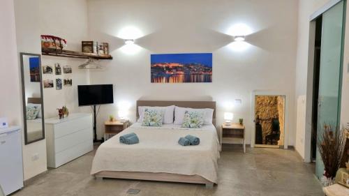 a bedroom with a bed with two tables and a tv at La Grotticella in Sciacca