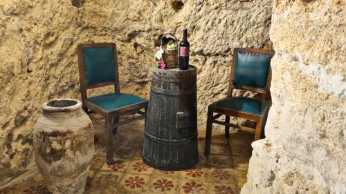a room with two chairs and a barrel with wine bottles at La Grotticella in Sciacca