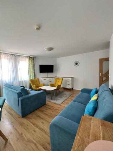 ein Wohnzimmer mit einem blauen Sofa und einem Tisch in der Unterkunft Al-Dom Apartamenty Olymp 204 in Kołobrzeg