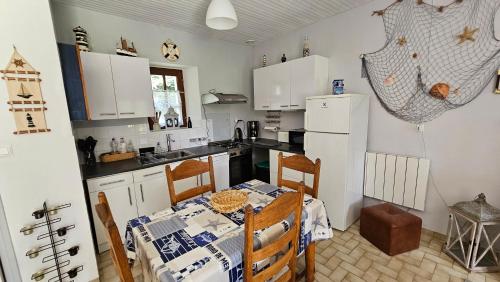 een keuken met een tafel en een witte koelkast bij Keryerna Ar C'haouled "aux Hortensias" clévacance in Saint-Méen