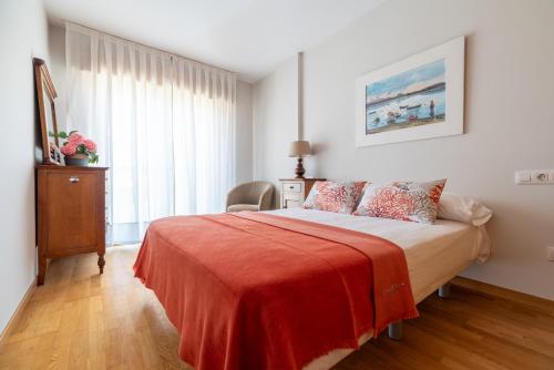 1 dormitorio con 1 cama con manta roja en Baiona Playa, en Baiona