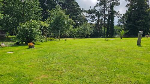 a large grass field with trees and a fence at Keryerna Ar C'haouled "aux Hortensias" 3 clévacance in Saint-Méen