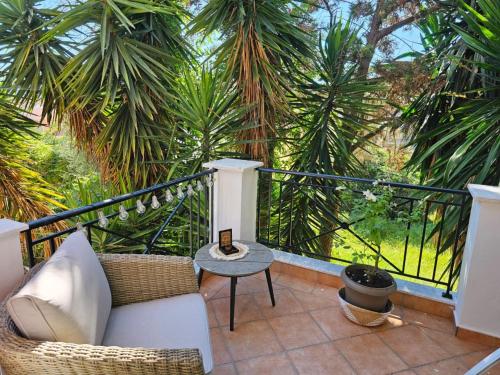 einen Balkon mit einem Sofa, einem Tisch und Palmen in der Unterkunft Corfu Villa Kanoni in Kanoni