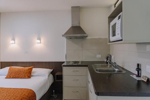 una pequeña cocina con cama y lavabo en Motel 429 en Hobart