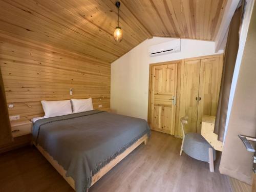 1 dormitorio con 1 cama y pared de madera en ALANYA BUNGALOW EVLERİ / RESTAURANT en Asmaca