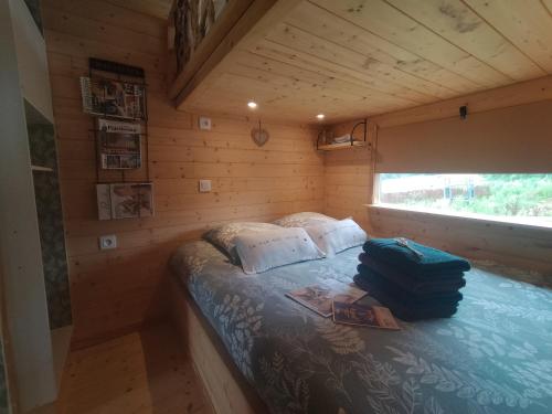 Ce lit se trouve dans une cabane en bois dotée d'une fenêtre. dans l'établissement La roulotte de Jane, à Margon