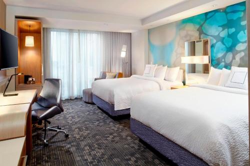 a hotel room with two beds and a desk at Courtyard by Marriott Orlando Lake Nona in Orlando