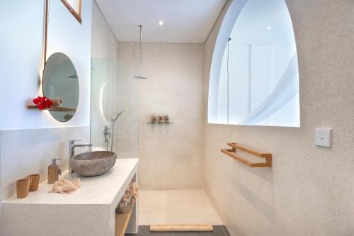 een badkamer met een wastafel en een douche met een spiegel bij Villa Zango, Ubud in Ubud
