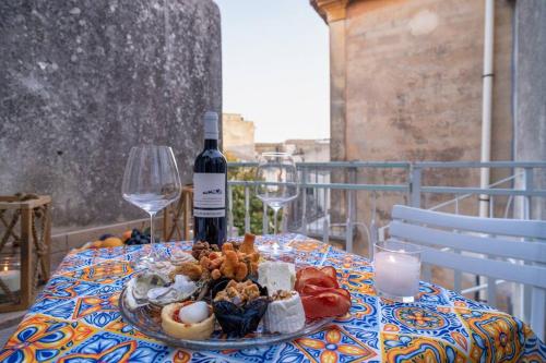 - une table avec une assiette de nourriture et une bouteille de vin dans l'établissement Maiolica Rooms Appartamento Ragusa Ibla, à Raguse