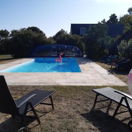 una piscina con 2 sillas y una persona en el agua en Les gîtes de Tréguennec, en Tréguennec