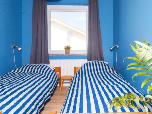 2 camas en una habitación con paredes azules y ventana en Holiday Home Sandnæshagevej II en Lild Strand