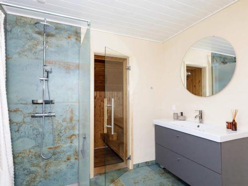 ein Bad mit einer Dusche, einem Waschbecken und einem Spiegel in der Unterkunft Holiday Home Sandnæshagevej II in Lild Strand