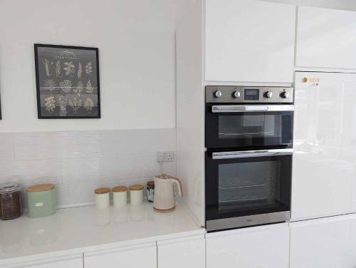 a kitchen with a black oven and white cabinets at Cosy Bee in Bournemouth