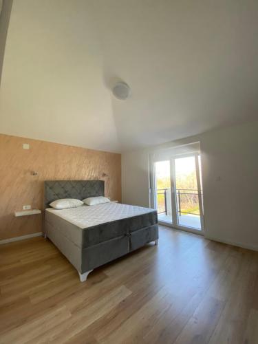 ein großes Schlafzimmer mit einem Bett und einem Holzboden in der Unterkunft Vila Mikeli in Podgorica