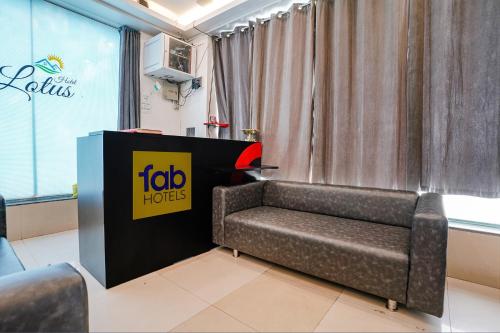 a couch in a room with a booth with a sign at FabHotel Lotus I in Surat