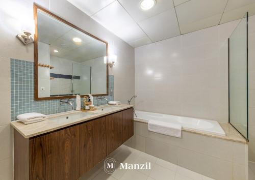 a bathroom with a tub and a sink and a mirror at Manzil - Stylish 3BR in Palm w Private Beach & Sea View in Dubai