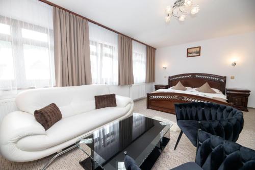 a living room with a white couch and a bed at Hotel Jelinek in Špindlerův Mlýn