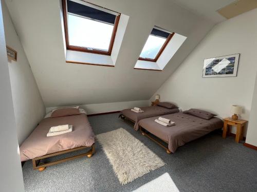 two beds in a room with two windows at Appartement Oz en Oisans in Oz