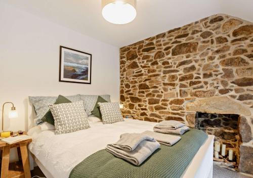 a bed in a room with a stone wall at Ty Fin in Llanbedrog